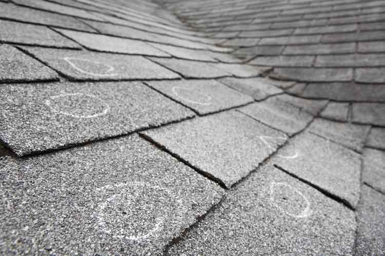 a gray shingled roof with hail damage indicated with chalk.