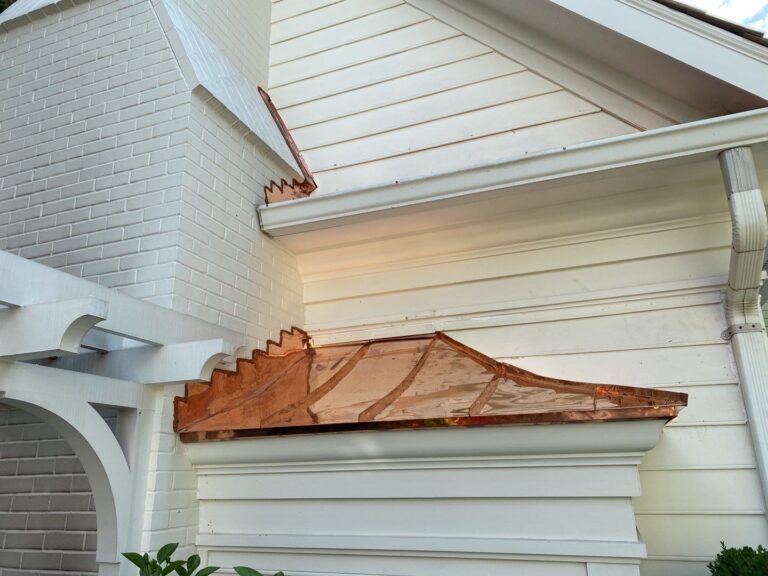 Close up of a standing seam copper statement roof on a butter cream colored James Hardie siding home.