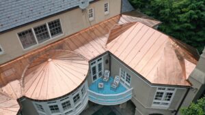 This photo is a bird's eye view of a beautiful custom-fabricated standing seam copper roof home in Washington DC. The intricate work done on the round sunroom, topped with a cupola, is a spectacular specimen of metalwork performed by American Custom Contractors technicians.