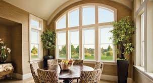 Picture of a light-filled room. The perspective is looking out a gorgeous large arched energy-efficient picture window overlooking a green space.