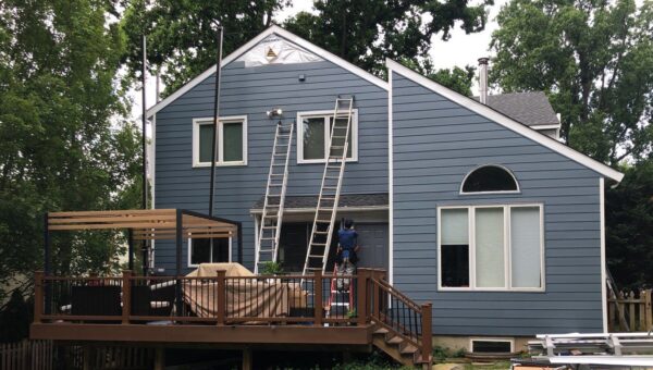 A modern style home with a contractors installing blue insulated siding