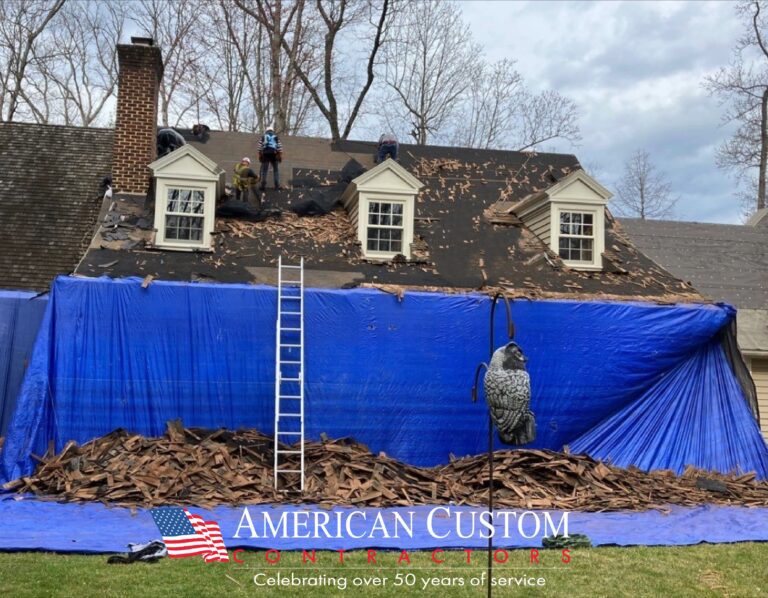Picture of a home that is having it's old roof shingles removed in preparation for a roof install. Big blue tarp protecting the front of the home