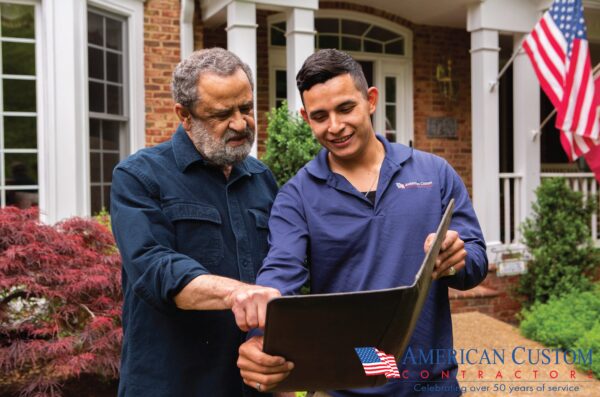 a young male project consultant speaking with a homeowner about theri roofing project while standing in front of his brick home. The homeowner is searching the DMV area for the best roofing company.