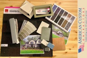 Picture of a table with various samples including shingle, siding, color, wood, and vent covers. All laid out on a wood table.