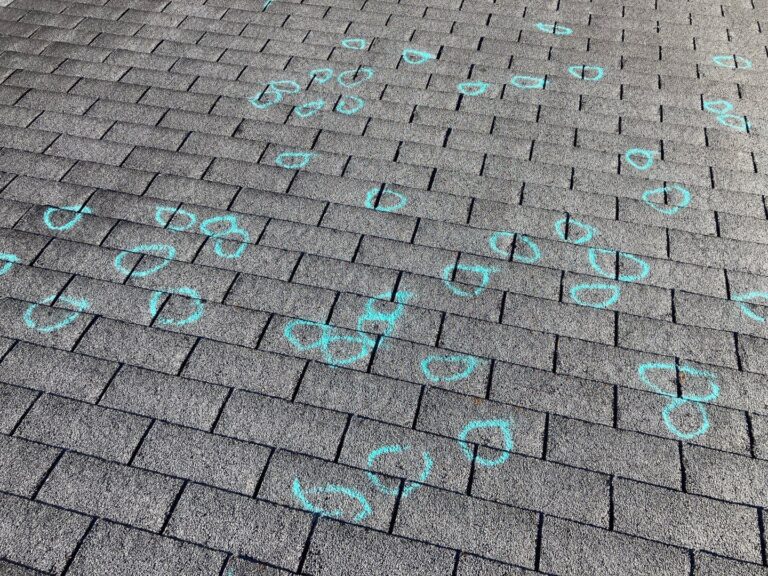 This image shows an asphalt shingle roof with various areas marked by circles, typically done to indicate storm damage, particularly hail damage. The marks identify spots where hail has caused dents, bruising, or other damage to the shingles, which could lead to potential leaks or other roofing issues over time.