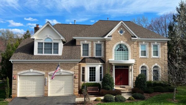 2-story brick house with Dormer window over the double garage. The from door is painted a dark red and there is an American flag on a flag pool over the garage door. The picture was taken on a sunny day with a bright blue sky behind the facade. We use this picture on our Rockville, Maryland service page.