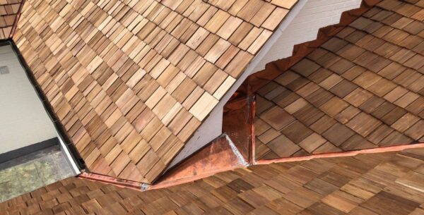 Natural cedar shake roof detail with a copper valley on a white house.
