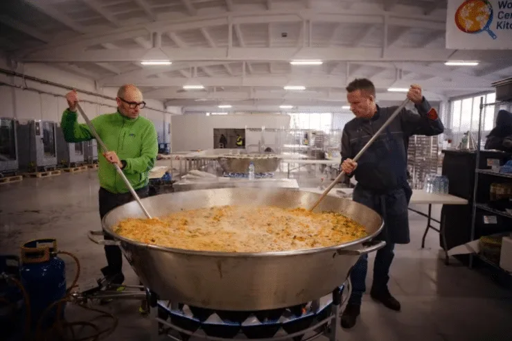 two men stirring a pot