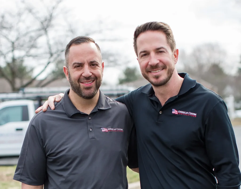 Two brothers wearing company polo shirts outside who are second-generation owners of American Custom Contractors. A roofing, siding, windows, gutters, and doors contractor in Maryland. This photo is used on our website testimonials page, about us page, and contact us page.