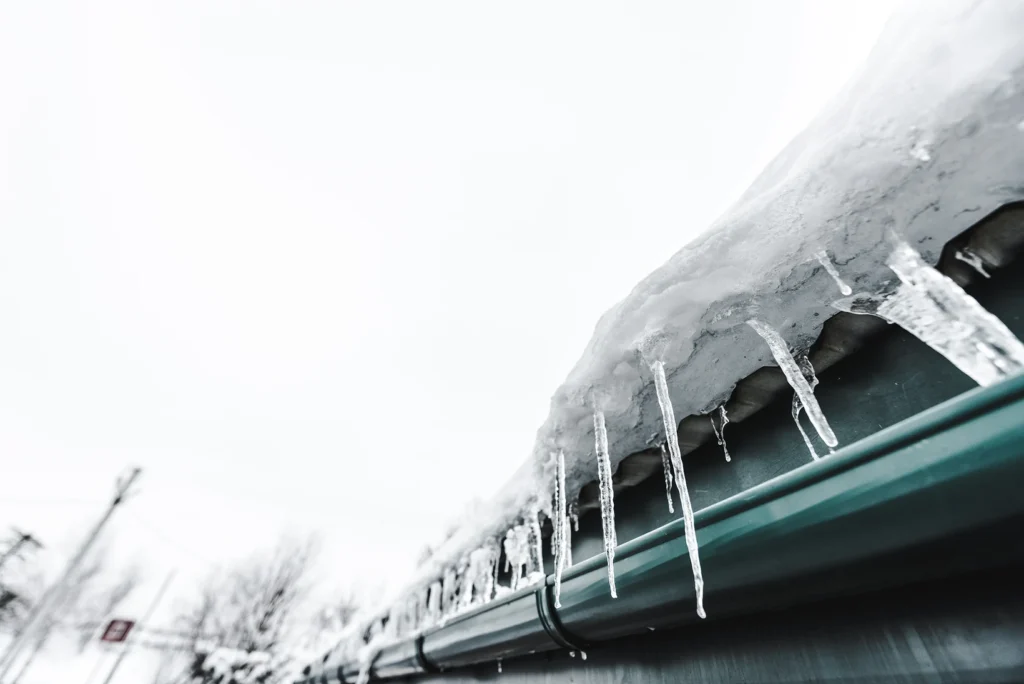 large icicles hanging from the gutter of a brick home.