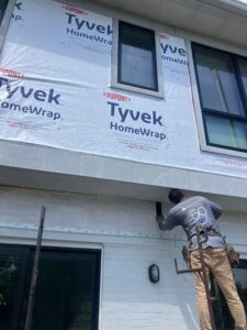 American Custom Contractors installer applying DuPont Tyvek HomeWrap during a siding installation on an Ellicott City, Maryland home — a key step in improving energy efficiency and reducing heat loss.