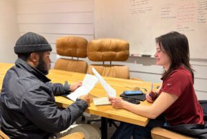 Two American Custom Contractors employees collaborating during on-the-job training in an office, highlighting career growth and skilled trade opportunities.