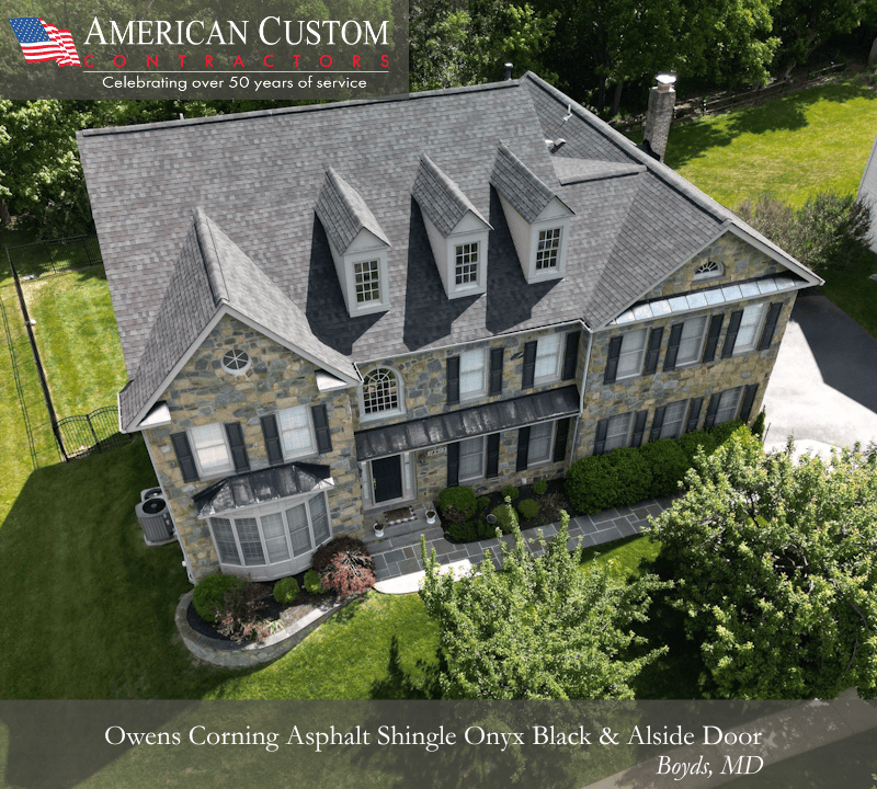 Drone photo of a recently completed roof by American Custom Contractors. On the photo is states that the project was in Boyds, Maryland, and they installed Owens Corning Asphalt Shingle in the color Onyx black as well as a Alside door on the this 2 story natural stone home. The image is used for the blog post, "Why Homeowners Chose American Custom Contractors as their exterior contractors in Maryland"