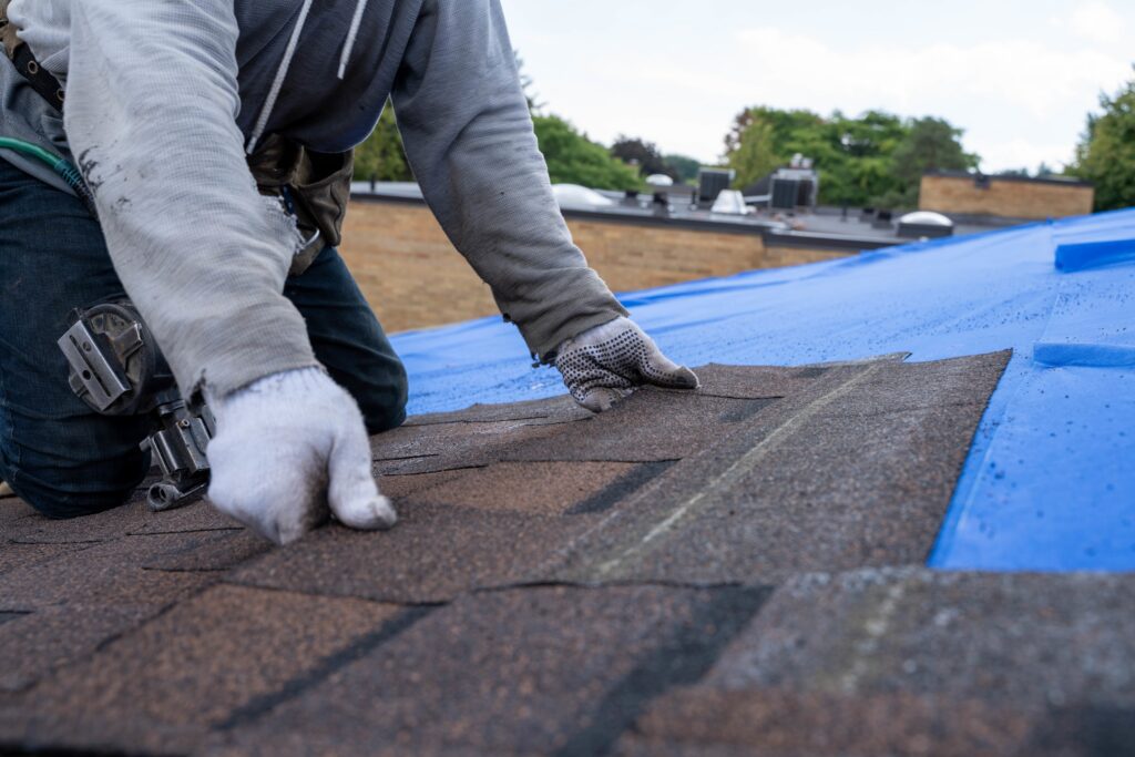 Roofers installing new roof on house, laying shingles on top of underlayment