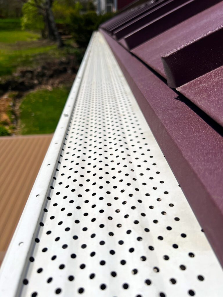 Gutter guards or leaf guard filters on the eves of a metal roof.