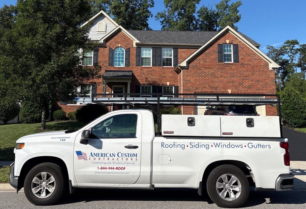 American Custom Contractors service truck parked outside a brick home in Severn, Maryland, offering roofing, siding, window, and gutter inspections