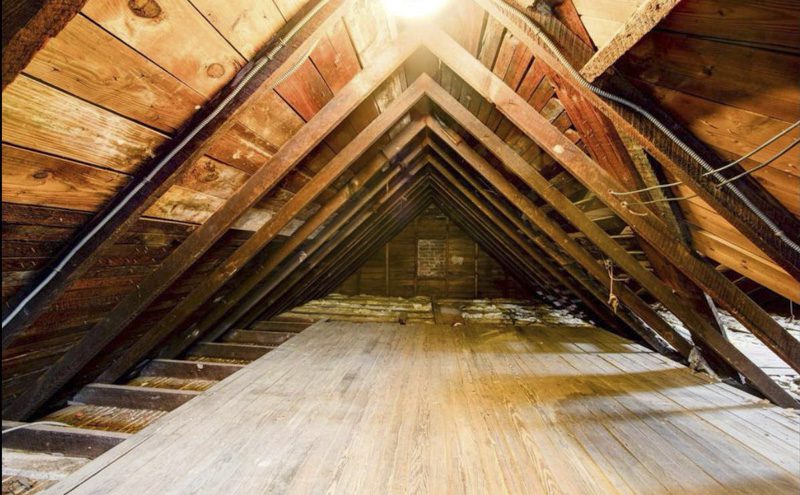 View inside a home attic with wooden roof framing, where roof inspectors check for water stains and moisture damage